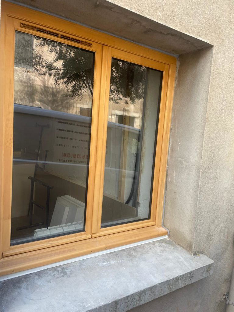 Fenêtre en bois posée dans une façade enduite