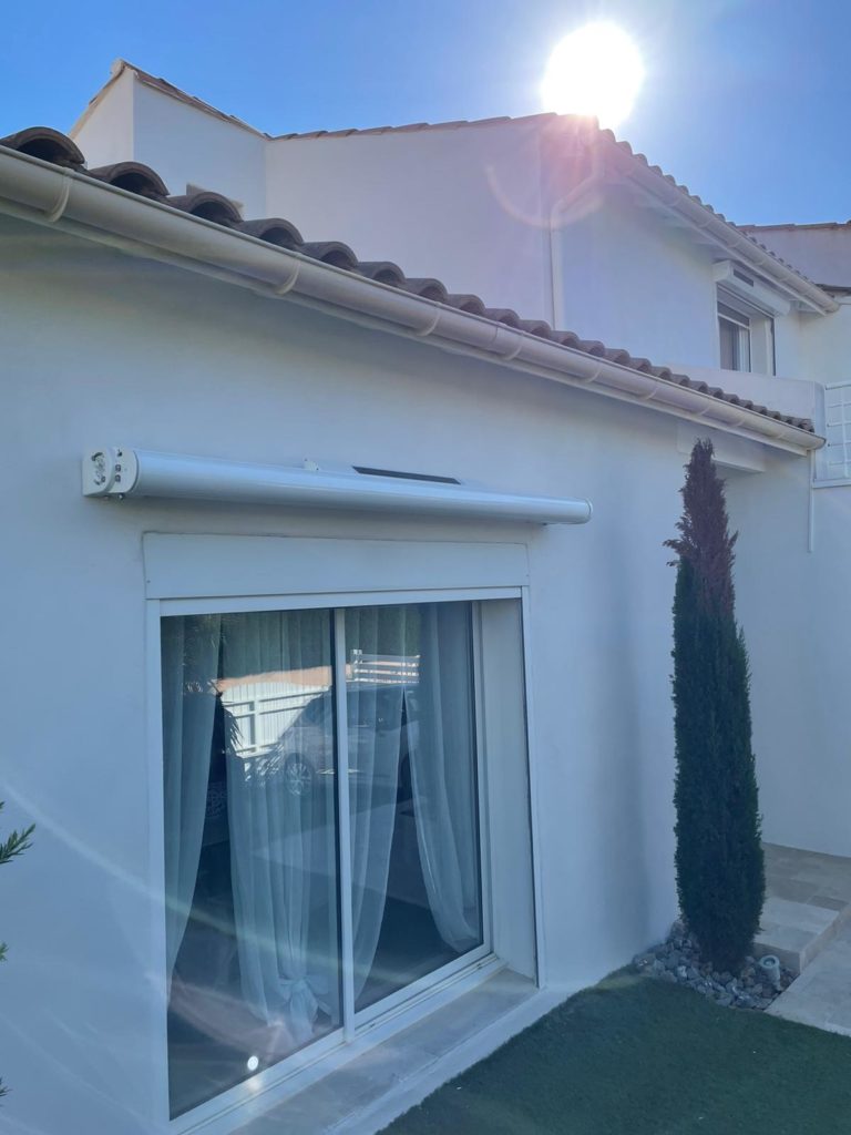 Baie vitrée coulissante avec volet roulant posée sur une maison blanche