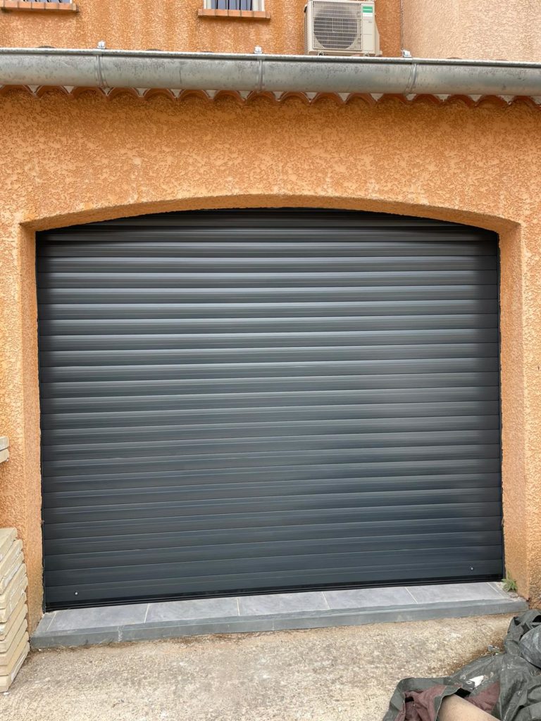 Porte de garage enroulable anthracite posée sur une façade ocre