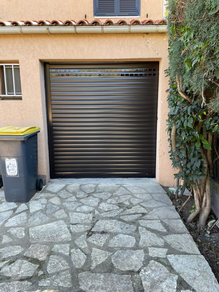 Porte de garage enroulable marron au bout d'une allée en pierre