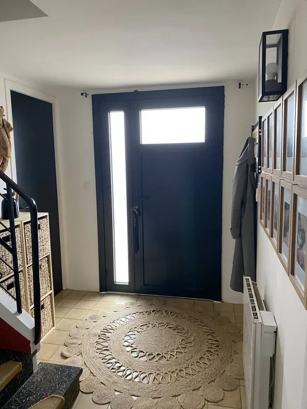 Porte d'entrée anthracite avec vitrage en partie haute et fixe latéral vitré, vue depuis l'entrée intérieure