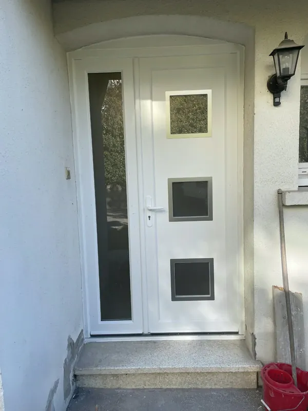 Porte d'entrée blanche à hublots carrés avec fixe latéral vitré, sous un encadrement cintré