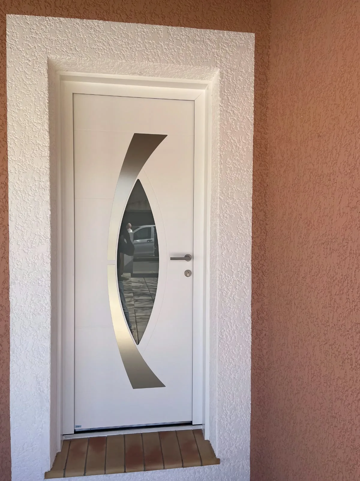 Porte d'entrée blanche avec vitrage ovale et décor inox