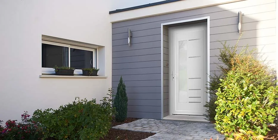 Maison contemporaine avec bardage gris et porte d'entrée blanche